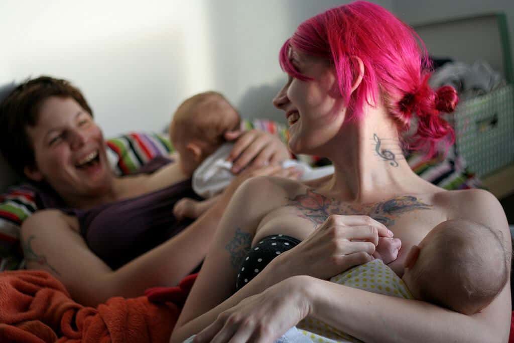 Two women laughing and breastfeeding their babies togeher