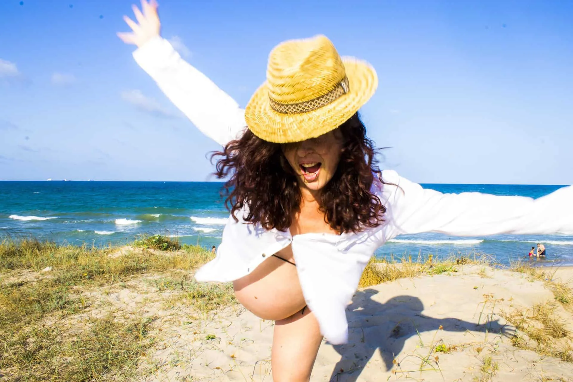 A Pregnant woman laughing and playing on a beach